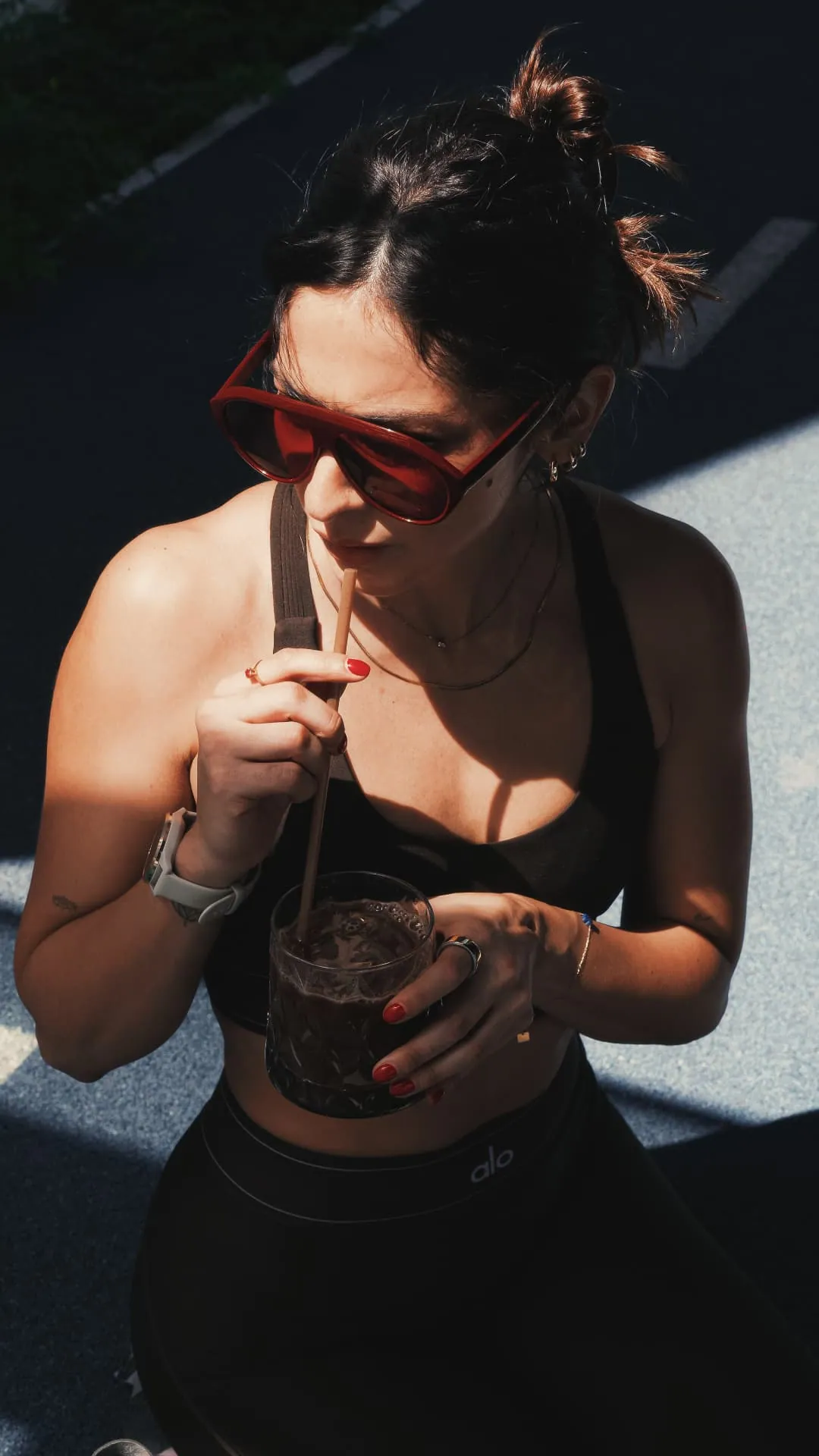 Mujer en ropa deportiva bebiendo café NÖMA frío con sorbete