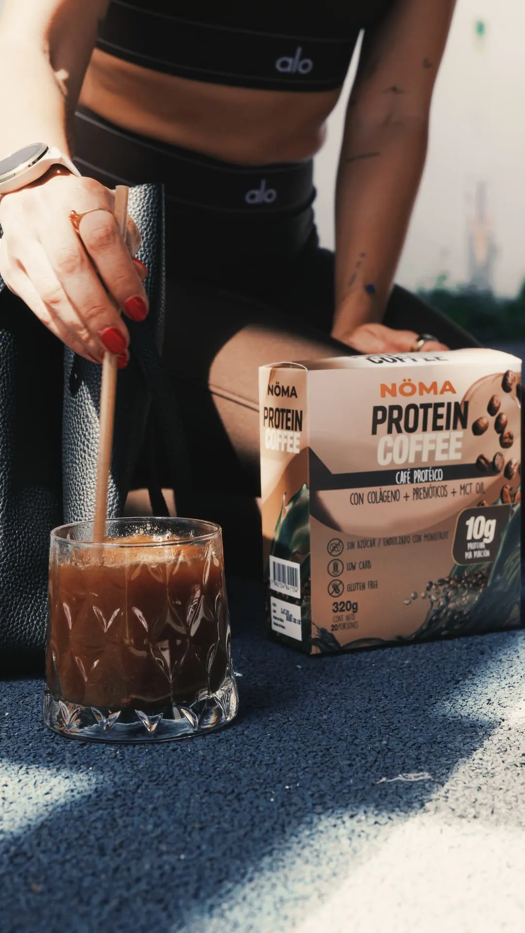 Mujer en ropa deportiva revolviendo su café NÖMA después de entrenar